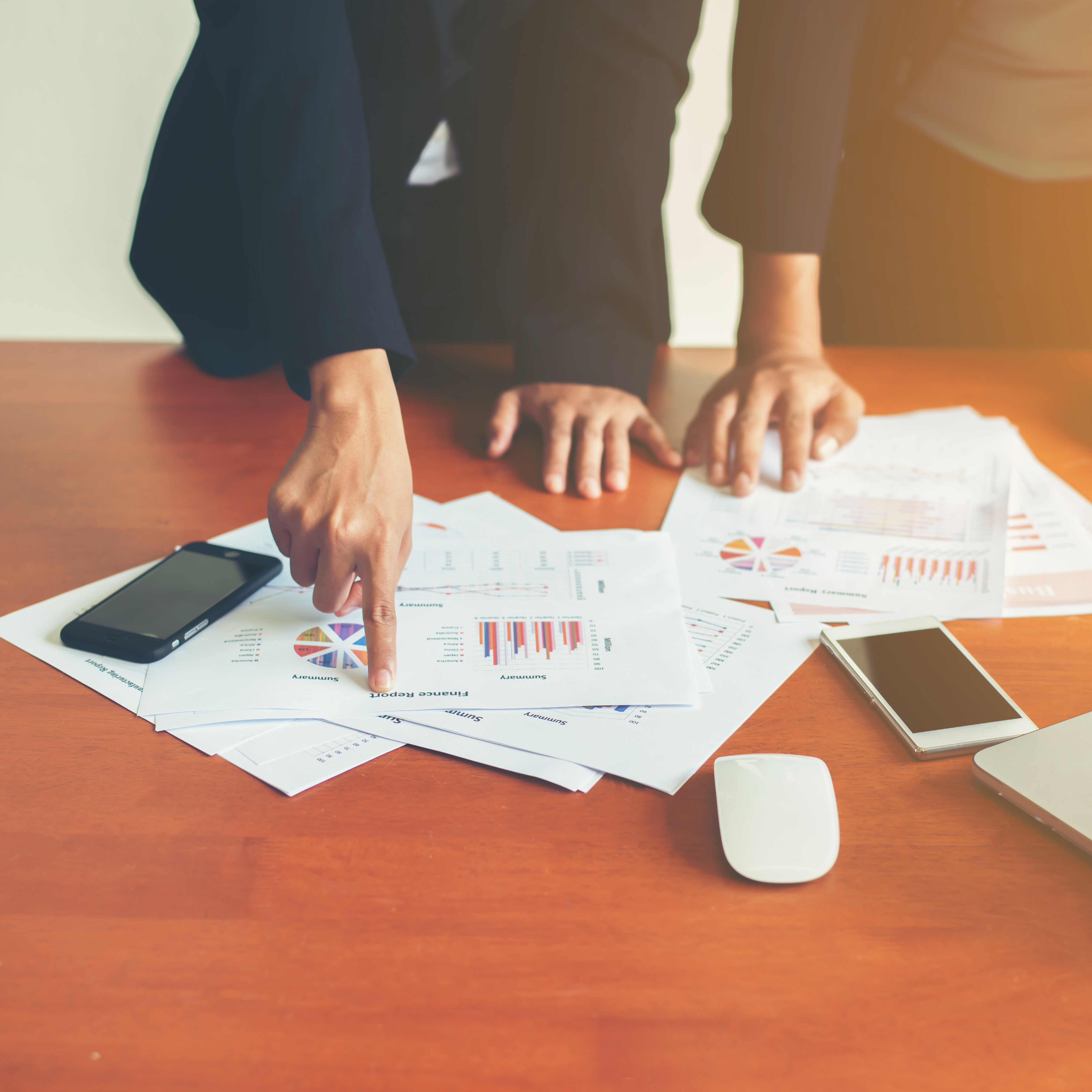 Two people reviewing printed financial reports on a desk.